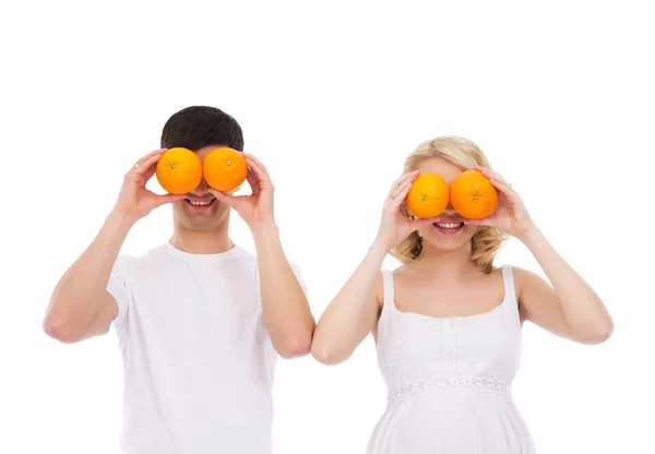 Ein glückliches Paar spielt mit Orangen auf weißem Hintergrund — Stockfoto