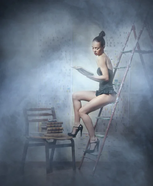 Hermosa mujer en lencería está leyendo un libro sobre el fondo ahumado —  Fotos de Stock