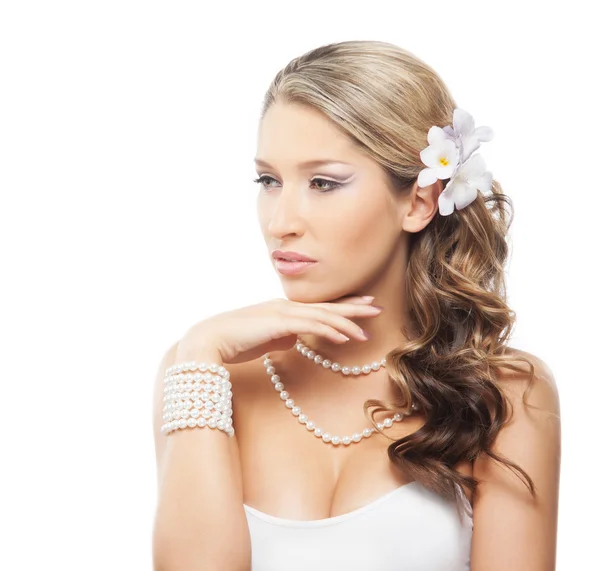 Mooie vrouw met een parel sieraden en een bloem in het haar — Stockfoto
