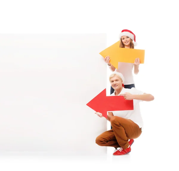 Три счастливых подростка в рождественских шляпах указывают на большой блан — стоковое фото