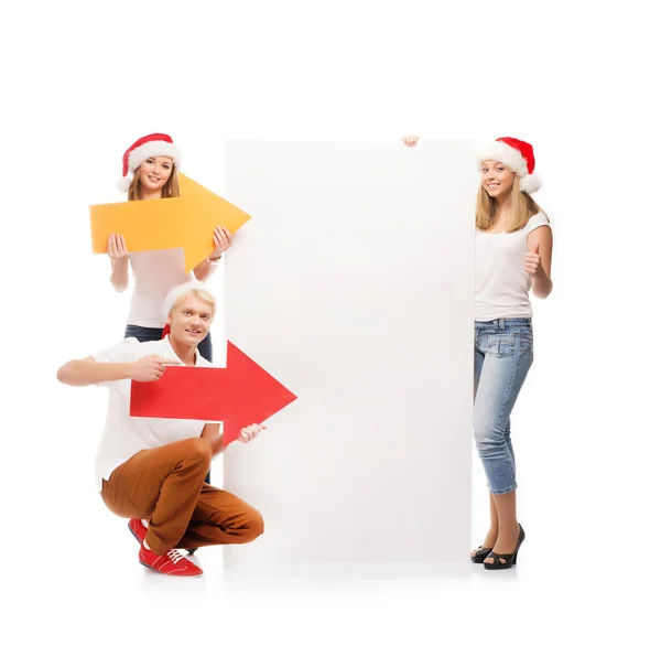 Tres adolescentes felices en sombreros de Navidad señalando un gran blan — Foto de Stock