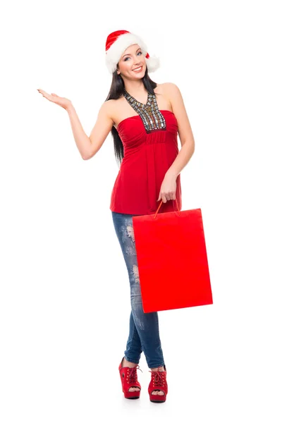 Uma mulher feliz em um chapéu de Natal segurando um saco de compras vermelho — Fotografia de Stock