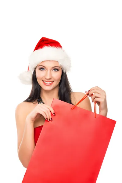 Una mujer feliz en un sombrero de Navidad sosteniendo una bolsa de compras roja —  Fotos de Stock