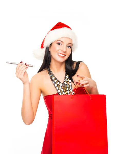 Uma mulher feliz em um chapéu de Natal segurando um saco de compras vermelho — Fotografia de Stock