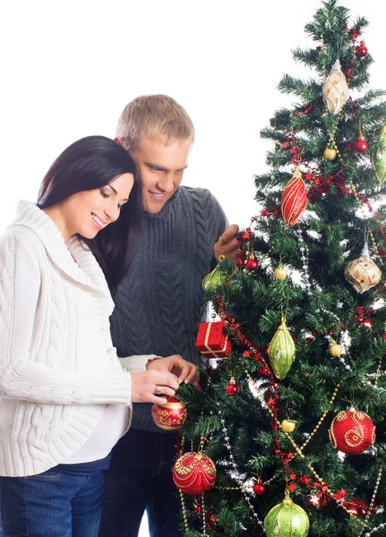 Těhotná žena a šťastný muž pózuje u vánočního stromu — Stock fotografie