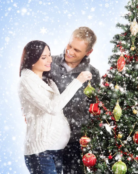 A pregnant woman and a happy man posing near the Christmas tree — Stock Photo, Image