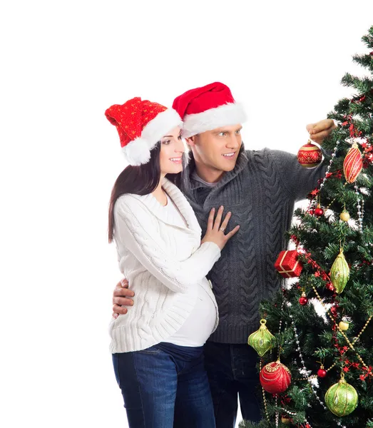 Těhotná žena a šťastný muž pózuje u vánočního stromu — Stock fotografie
