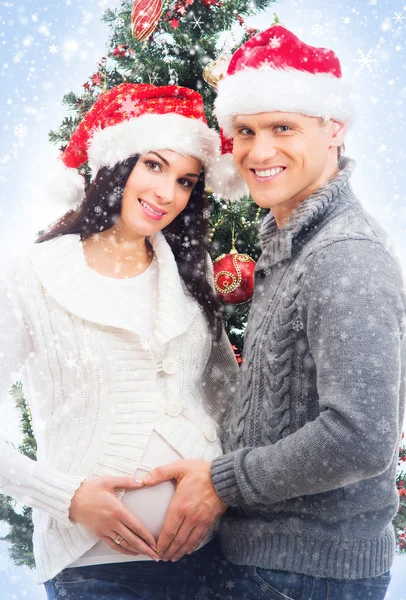 A pregnant woman and a happy man posing near the Christmas tree — Stock Photo, Image