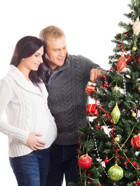 Uma mulher grávida e um homem feliz posando perto da árvore de Natal — Fotografia de Stock