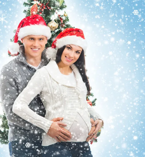 A pregnant woman and a happy man posing near the Christmas tree — Stock Photo, Image
