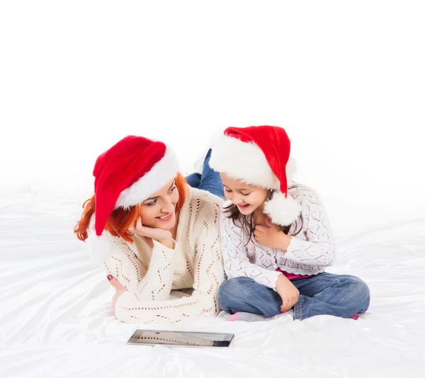 Eine glückliche Mutter und eine Tochter entspannen sich in roten Weihnachtsmützen — Stockfoto