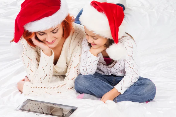 A happy mother and a daughter relaxing in red Christmas hats — Stock Photo, Image