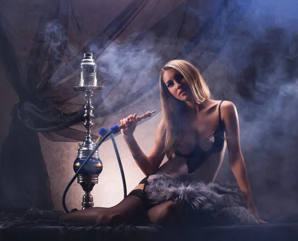 Una joven rubia en lencería sexy fumando una cachimba — Foto de Stock