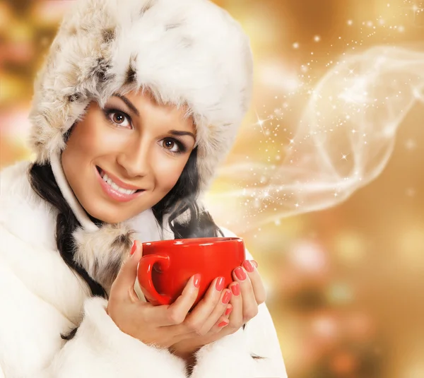 Mujer joven y hermosa con una taza roja sobre la Navidad abstracta —  Fotos de Stock