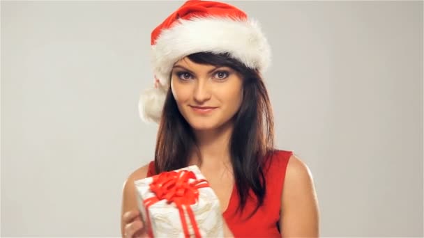 Una mujer feliz con un sombrero de Navidad sosteniendo un regalo — Vídeos de Stock