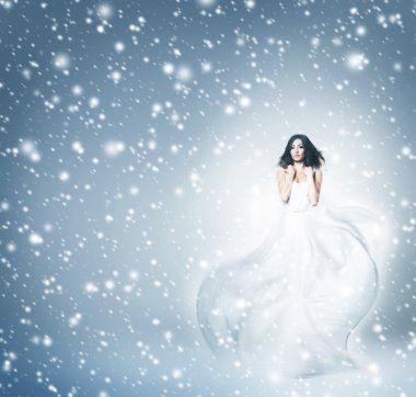 genç ve güzel bir kadın elbise gri arka plan üzerinde üfleme içinde