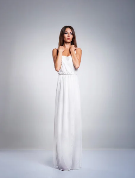 Een jonge brunette vrouw in een lange witte jurk — Stockfoto