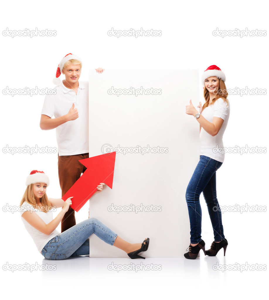 Three happy teenagers in red Christmas hats posing next to a white banner