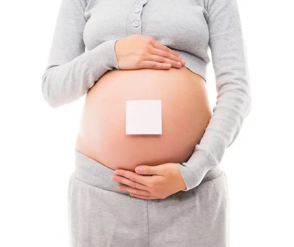 Buik van een jonge zwangere vrouw met een witte sticker — Stockfoto