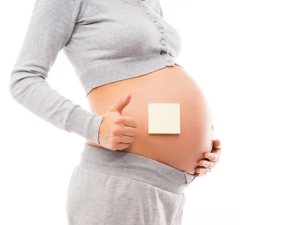 Belly of a young pregnant woman with a white sticker — Stock Photo, Image