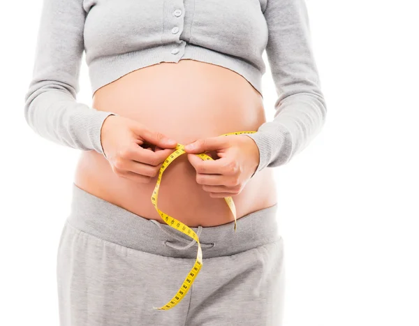 A pregnant woman measuring her belly with a tape — Stock Photo, Image