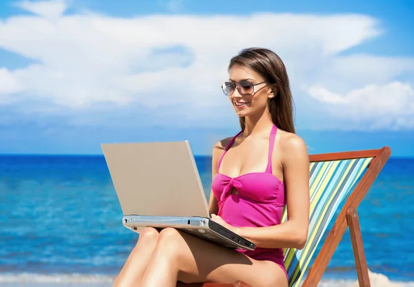 Une jeune femme brune en maillot de bain blanc se relaxant sur la plage — Photo