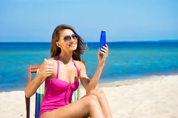 Une jeune femme brune en maillot de bain blanc se relaxant sur la plage — Photo