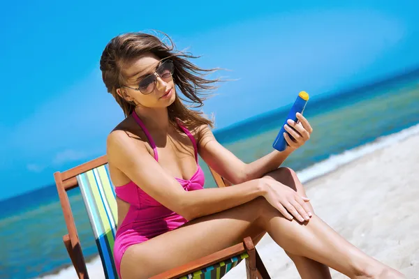 Een jonge brunette vrouw in een witte zwembroek ontspannen op het strand — Stockfoto
