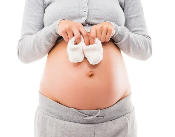 A pregnant woman with a belly holding baby shoes Royalty Free Stock Photos