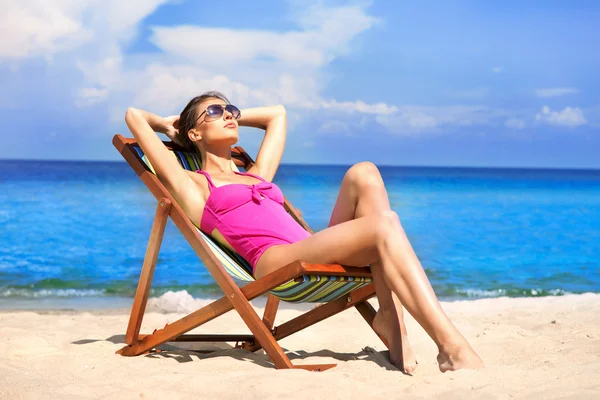 A young brunette woman in a white swimsuit relaxing on the beach Royalty Free Stock Photos