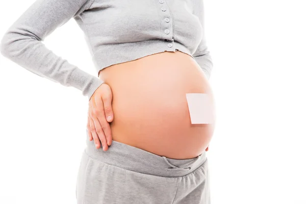 Belly of a young pregnant woman with a white sticker — Stock Photo, Image