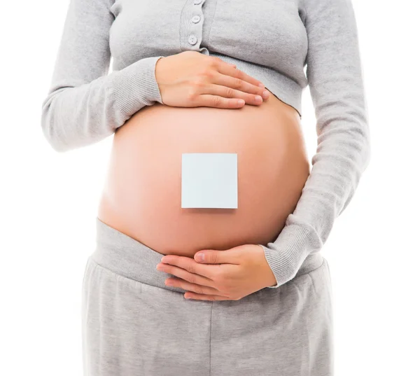 Buik van een jonge zwangere vrouw met een witte sticker — Stockfoto