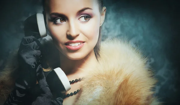 A young woman in luxurious clothes talking on a retro phone — Stock Photo, Image