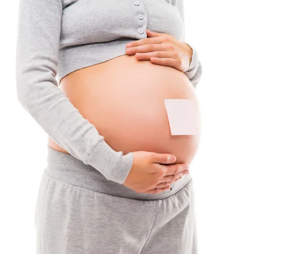 Buik van een jonge zwangere vrouw met een witte sticker — Stockfoto