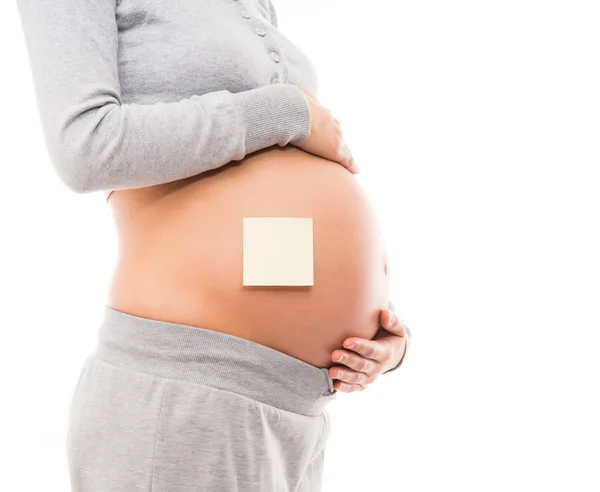 Belly of a young pregnant woman with a white sticker Royalty Free Stock Images