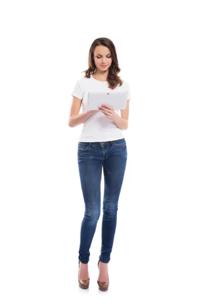 Uma menina jovem e feliz em jeans elegantes segurando um tablet computar — Fotografia de Stock