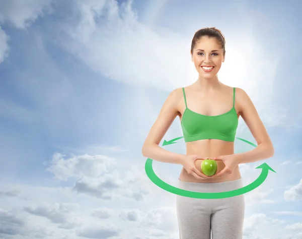 Joven mujer deportiva atractiva con una manzana verde sobre el cielo —  Fotos de Stock