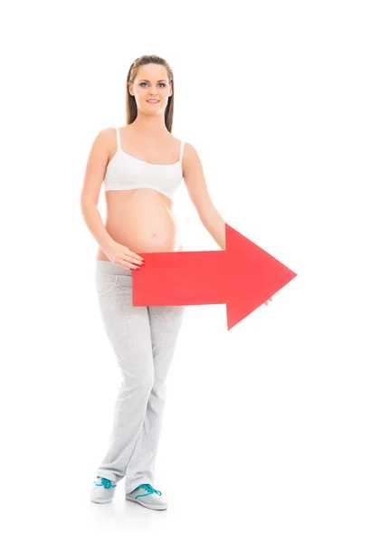 年轻的金发怀孕女子，捧着一个红色箭头 — 图库照片