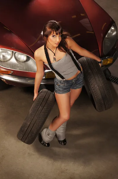 Young and sexy woman repairing a retro car in a garage — Stock Photo, Image