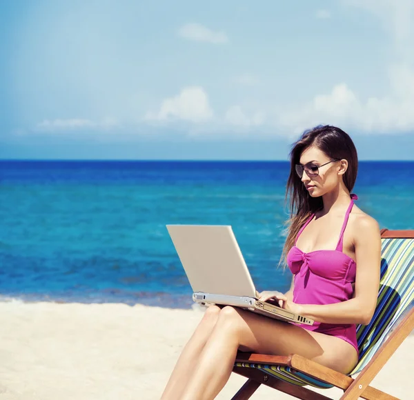 Une jeune femme se relaxant avec un ordinateur portable sur une belle plage Photos De Stock Libres De Droits