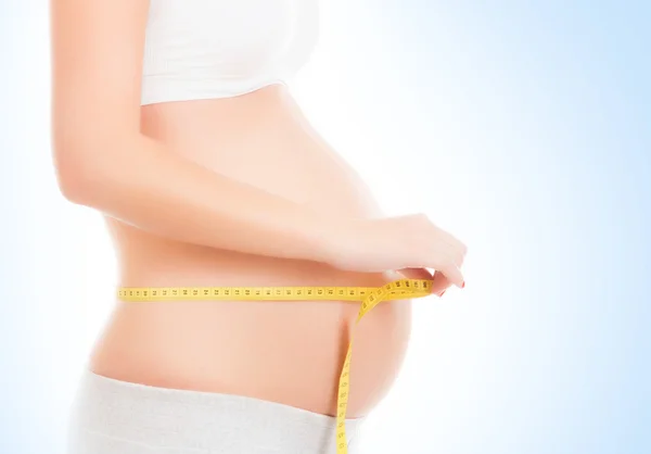 Mulher grávida medindo sua barriga — Fotografia de Stock