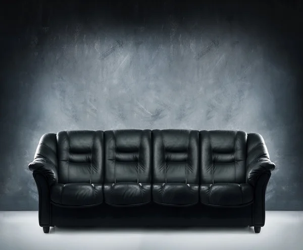 Black leather sofa in dramatic interior — Stock Photo, Image