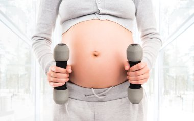 Pregnant woman working out with dumbbells clipart