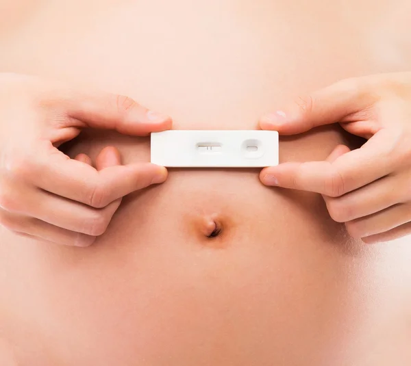 Pregnant woman holding a pregnancy test — Stock Photo, Image