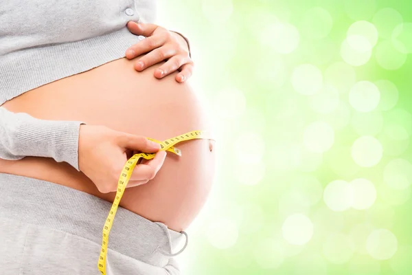 Pregnant woman measuring her belly with a tape — Stock Photo, Image