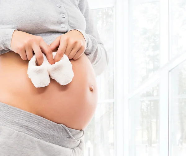 Pregnant woman with baby shoes — Stock Photo, Image