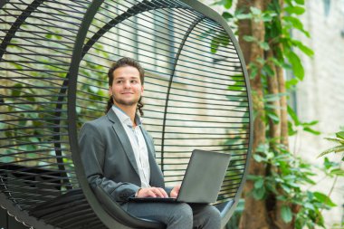 Genç başarılı beyaz iş adamı bir salonda bilgisayar kullanarak çalışıyor. İş, serbest meslek ve uzak çalışma.