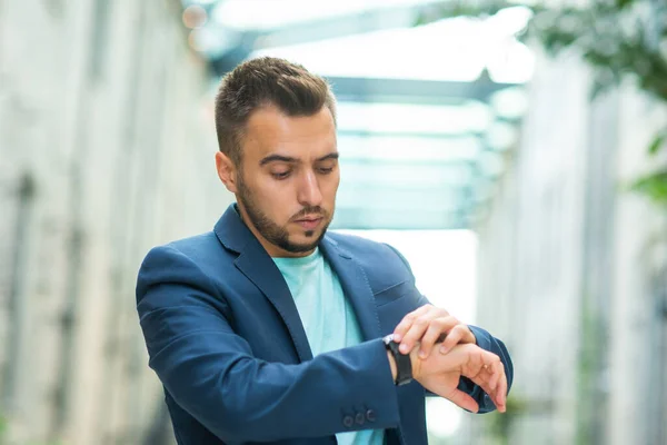 Un jeune homme d'affaires prospère travaille en plein air en utilisant smartwatch. Homme en tenue décontractée. Entreprises, freelance et télétravail. — Photo
