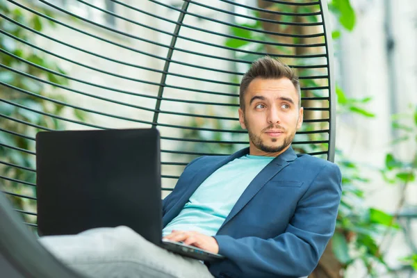 Joven empresario caucásico exitoso trabaja en un salón con una computadora. Negocios, freelance y trabajo remoto. — Foto de Stock