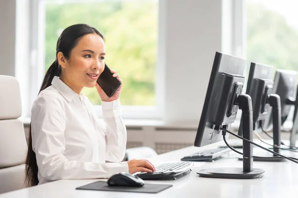 Donna d'affari asiatica sta lavorando al suo tavolo in un ufficio moderno. Il posto di lavoro di uno specialista di successo. Affari, fiducia e finanza. — Foto Stock